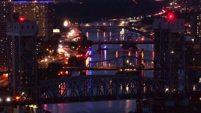 A mesmerizing parallax effect as the drone captures the stunning night view of the Third Ave, and Madison Ave bridges with a train crossing between them, against the backdrop of the NYC skyline.