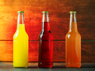 Three glass bottles of lemonade on a wooden table. Summer refreshing drinks