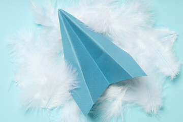 Paper plane and feathers on blue background