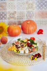 Vegetarian french salad with feta, edible flowers, figs, peach, basil on ceramic tile background...