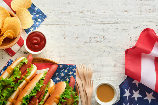4th of July American Independence Day traditional picnic food. Hot dog with potato chips and cocktail, American flags and symbols of  USA Patriotic picnic holiday on white wooden background. Top view