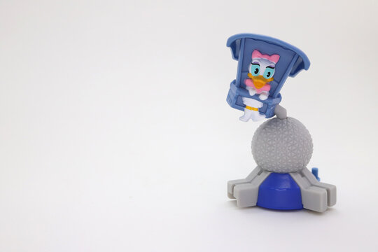 Daisy Duck in a flying game at Disney's Epcot park.  Spaceship earth. Animated character in amusement park. Collectible toy for children on white isolated background. Image with empty space for texts.