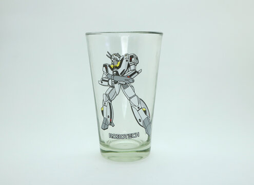 
Glass cup with a drawing of a robot from the Robotech television series. Animated character from the famous tv series of the 80s. Japanese anime character. Object on white background isolated.