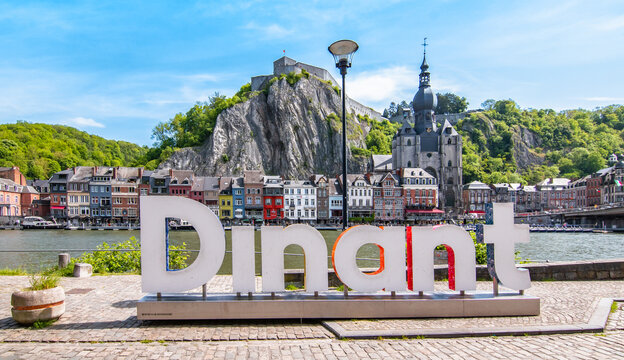 DINANT, BELGIUM - May 18, 2023: City centre of Dinant with large word sign along the Meuse river. Citadel in the background.