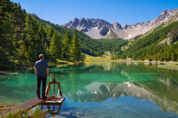 Man at lakeside of Orceyrette Lake in Summer in Briancon Region. Hautes-Alpes, French Alps, France