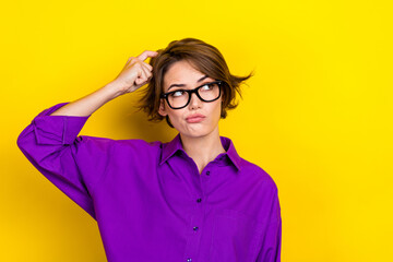 Creative manager photo of young woman wear purple shirt scratch finger head look empty space hmm ponder isolated on yellow color background