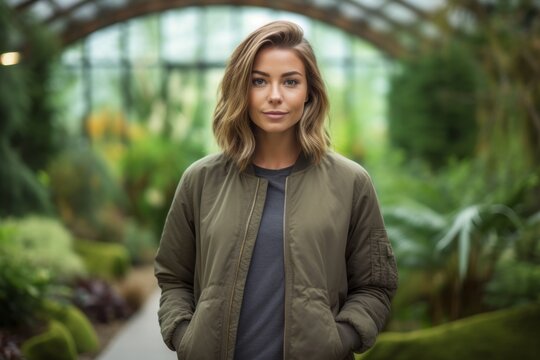 Lifestyle portrait photography of a glad mature girl wearing a sleek bomber jacket against a peaceful zen garden background. With generative AI technology