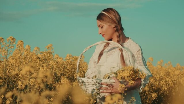 Beautiful young woman in white dress on yellow flower meadow in sunset