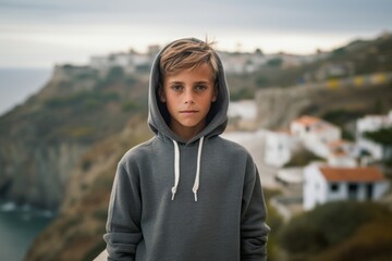 Lifestyle portrait photography of a glad kid male wearing a stylish hoodie against a scenic cliffside village background. With generative AI technology