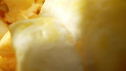 Macro video by a probe lens, the scattered popcorn on the floor. Reveals intricate details, its irregular shape, textured surface, and the remnants of butter and seasoning clinging to its crevices.

