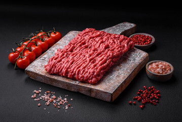 Raw ground beef or pork on a wooden cutting board with spices and salt