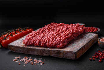 Raw ground beef or pork on a wooden cutting board with spices and salt