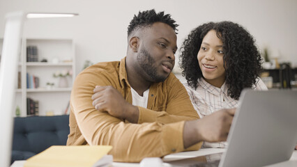 Smiling African American couple looking for an apartment or a house to buy online