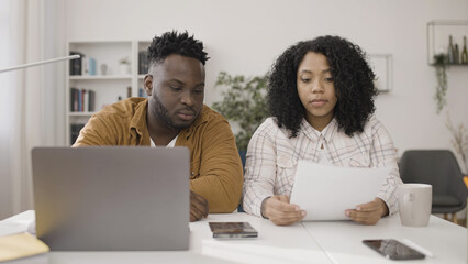 African American couple calculates their family budget in preparation for a large purchase, a house or car