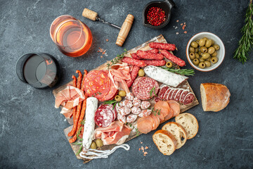 Salami, sliced ham, sausage, prosciutto, bacon, toasts, olives. Meat antipasto platter and red wine