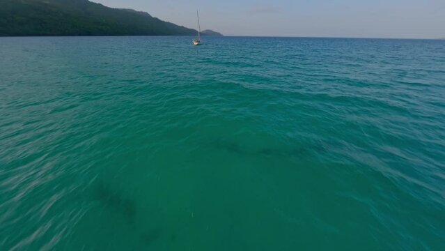 Fpv dynamic drone flight over Caribbean Sea , orbiting sailboat near playa rincon beach, samana