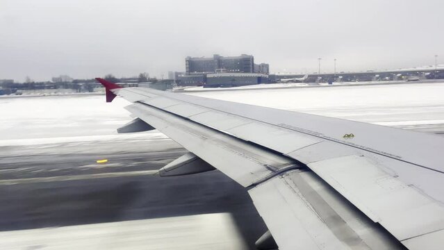 The wing of a accelerating and taking off airplane from a snow-covered runway at the airport