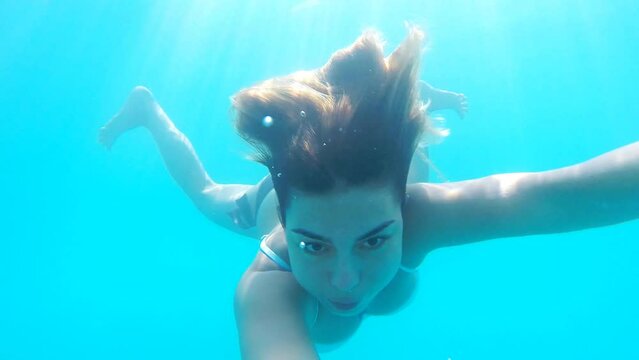 Portrait of young woman diving in sea. Girl swimming under water and filming himself. Female tourist enjoying resting on resort at summertime. Underwater footage. Summer vacation or travel concept