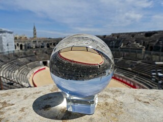Nîmes, May 2023 : Visit the beautiful city of Nîmes en Provence - Historical city with its arena and ancient theater - View on the arena Through a lens ball - obrazy, fototapety, plakaty
