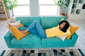 Portrait of positive relaxed lovely girl with wavy hairstyle dressed yellow sweatshirt lying on...