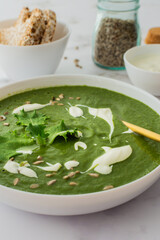 Healthy breakfasts, green broccoli and spinach cream soup with sunflower seeds and yogurt, buckwheat bread, top view