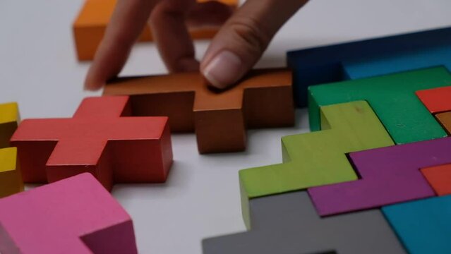 Closeup Slow motion. Hand holding piece of wooden block puzzle. wood cube stacking. Concept of complex and smart logical thinking.