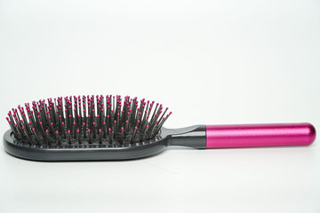 New modern black hairbrush with pink handle isolated on white.