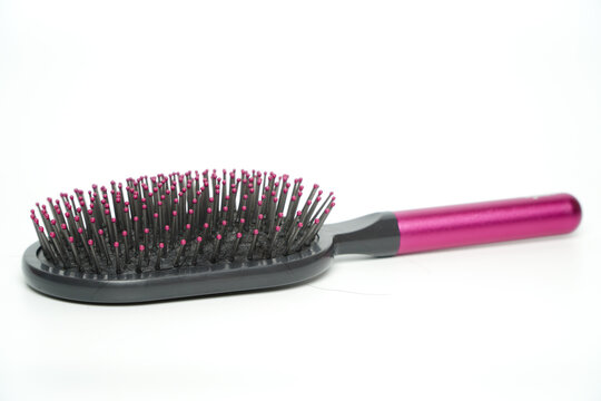 New modern black hairbrush with pink handle isolated on white.