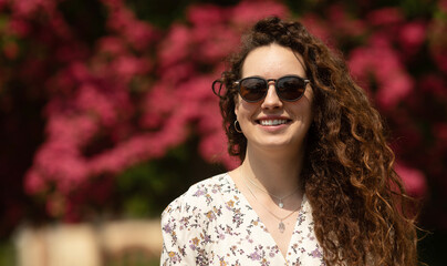 Portrait of a beautiful young woman with smile and sunglasses in the city. 