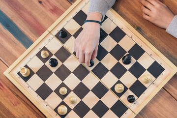 Table top view of the chessboard with the hand of a teenage girl playing