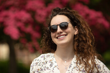 Portrait of a beautiful young woman with smile and sunglasses in the city. 