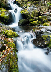 Blurred waterfall throughing mossy rocks