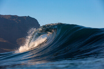 perfect wave breaking on a reef with mountain background