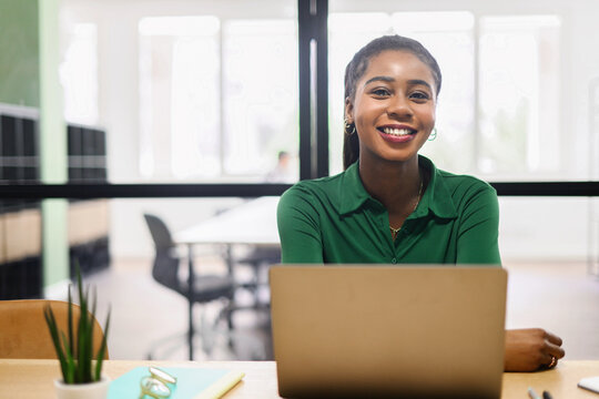 Portrait of concentrated african-american female employee using laptop computer, smiling black businesswoman responds emails, freelancer woman working on the distance sitting in coworking space