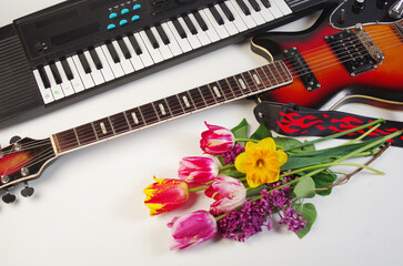 Musical instruments electric guitar and synthesizer, a bouquet of tulips and lilacs on a light...