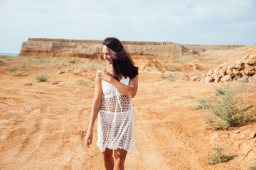 a woman in white clothes walking in a sandy desert