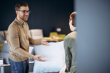 Couple chossing sofa and pillows at furniture store