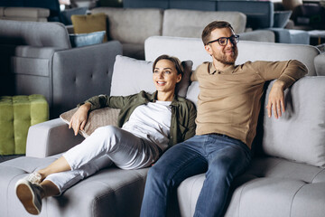 Couple choosing sofa and pillows at furniture store