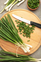 Cut green onion on grey concrete background.