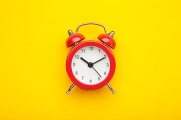 Red vintage alarm clock on yellow background. Space for text