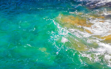 Fototapeta na wymiar Surfer waves turquoise blue water rocks cliffs boulders Puerto Escondido.