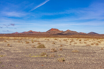 Sandy valley with hardened volcanic lava. In distance, the crater of the volcano. Canary mountains.