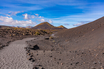 Winding road leading to the mountains. Sandy-clay soil. Mountain landscape under white clouds.