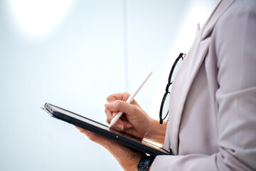 Portrait adult Asian business woman wearing suit holding and Using Digital Tablet Computer at office building