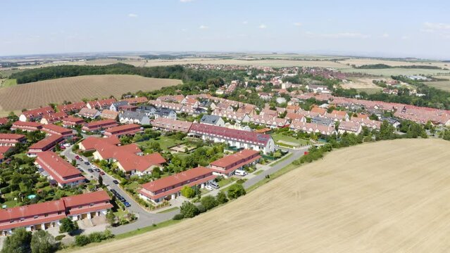 Aerial view from a drone - an idyllic, picturesque town with colorful houses surrounded by fields on a sunny day - drone drifts to the right