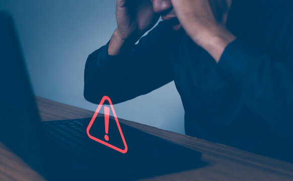 Businessman or it staffs, programmer, developer using computer laptop with triangle caution warning sign for notification error and maintenance concept. Hack system alert, warning computer system