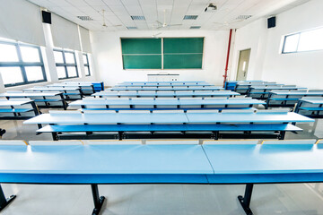 Bright university classroom with blue desks and chalkboard