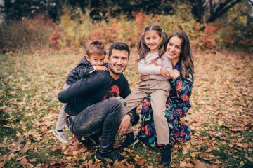 Happy smiling beautiful family playing and laugh in the forest