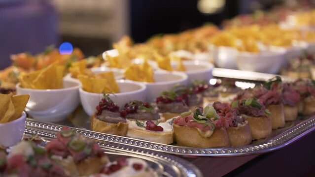 Canapés and tortilla chips on silver plates as part of catering - closeup