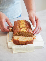 woman with knife in hand to cut freshly baked banana bread on the table.
